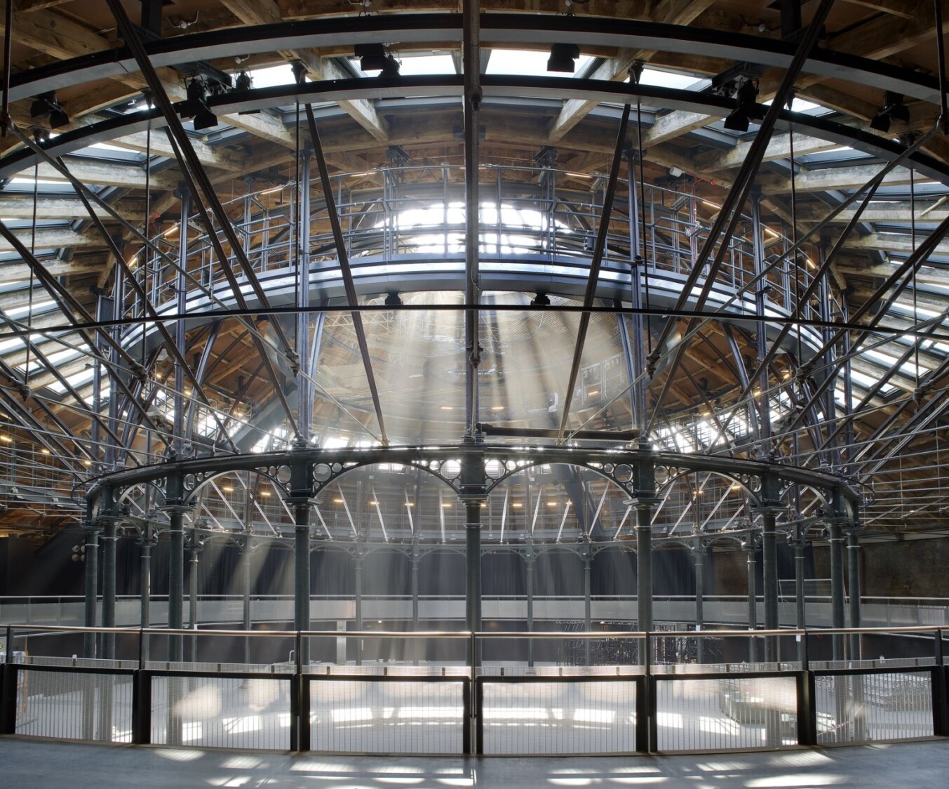 Interior view of the Roundhouse's iconic circular roof structure, featuring exposed metal beams, wooden rafters, and natural light streaming in through skylights.